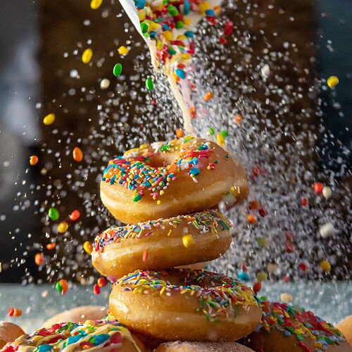 Firefly loads of sprinkles pouring onto a pile of bouncing doughnuts, action, moving, food photograp