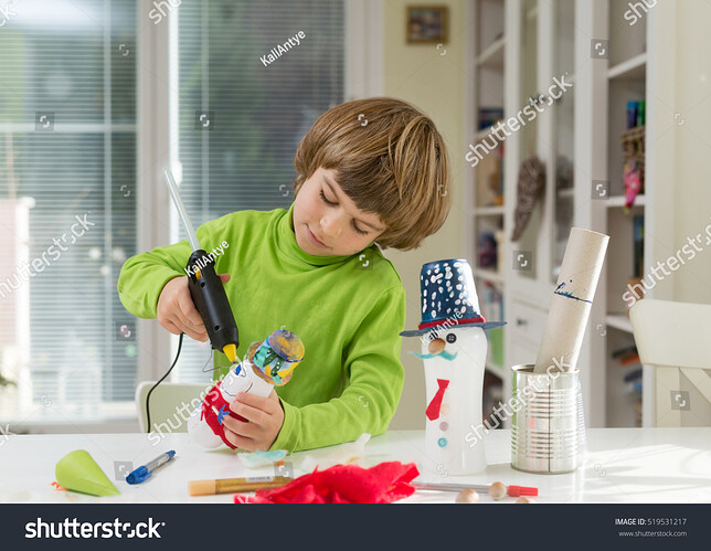 stock-photo-little-boy-being-creative-making-do-it-yourself-toys-out-of-yogurt-bottle-and-paper-using-hot-melt-519531217