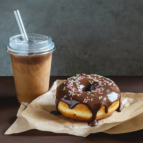 Firefly fresh donut with chocolate frosting and sprinkles wrapped in parchment paper laying on a bro