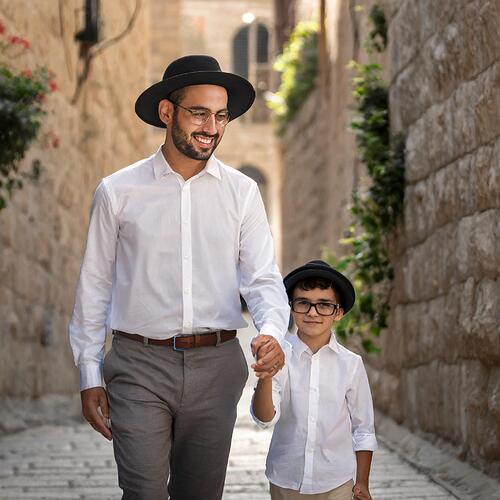 Firefly Israeli father wearing white button down shirt, black hat, talit, walking in the old city of (1)